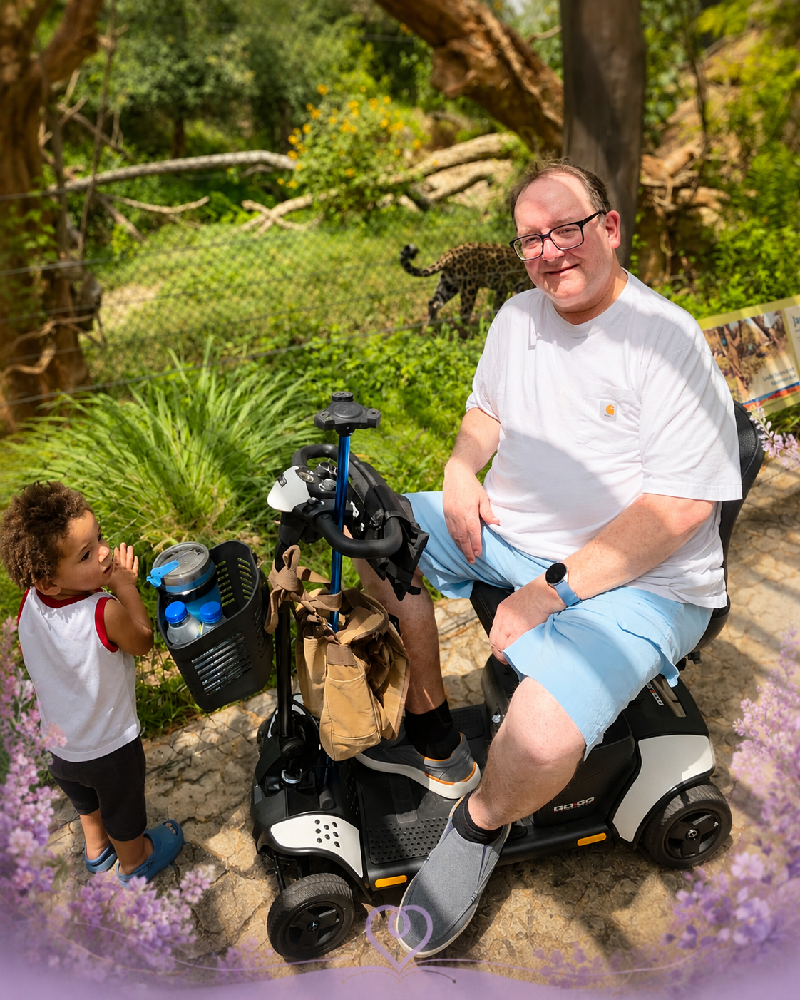 Randall seated on his mobility scooter during a zoo visit with a young child nearby